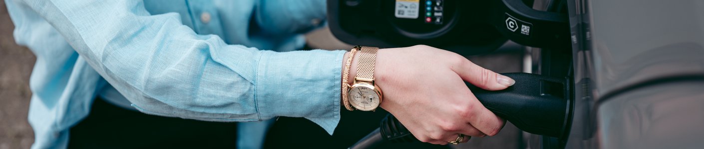 Ladestecker wird von einer Frau an das Elektrofahrzeug angeschlossen – E-Auto laden